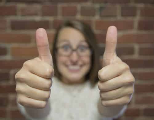 A woman holds both thumbs up explaining the difference between Botulinum Toxin Type A and Type B