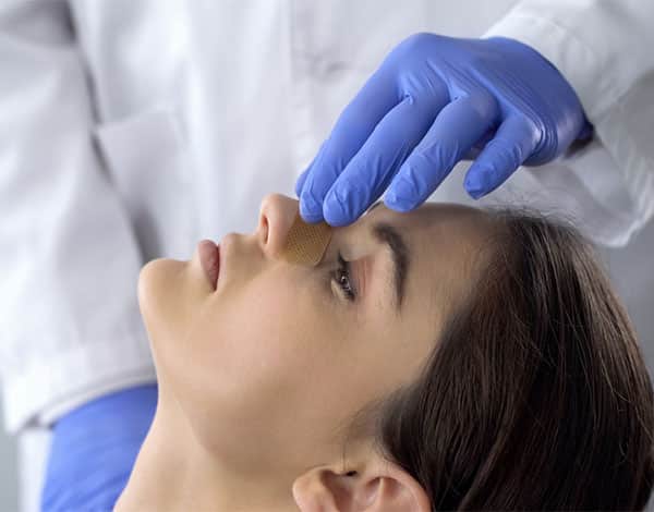 The doctor is preparing a woman for Non-Surgical Rhinoplasty