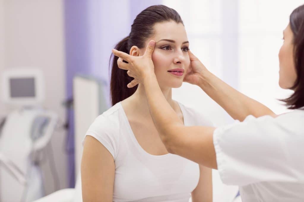 An aesthetic specialist assesses the forehead of a patient who wants to receive Dysport injections.