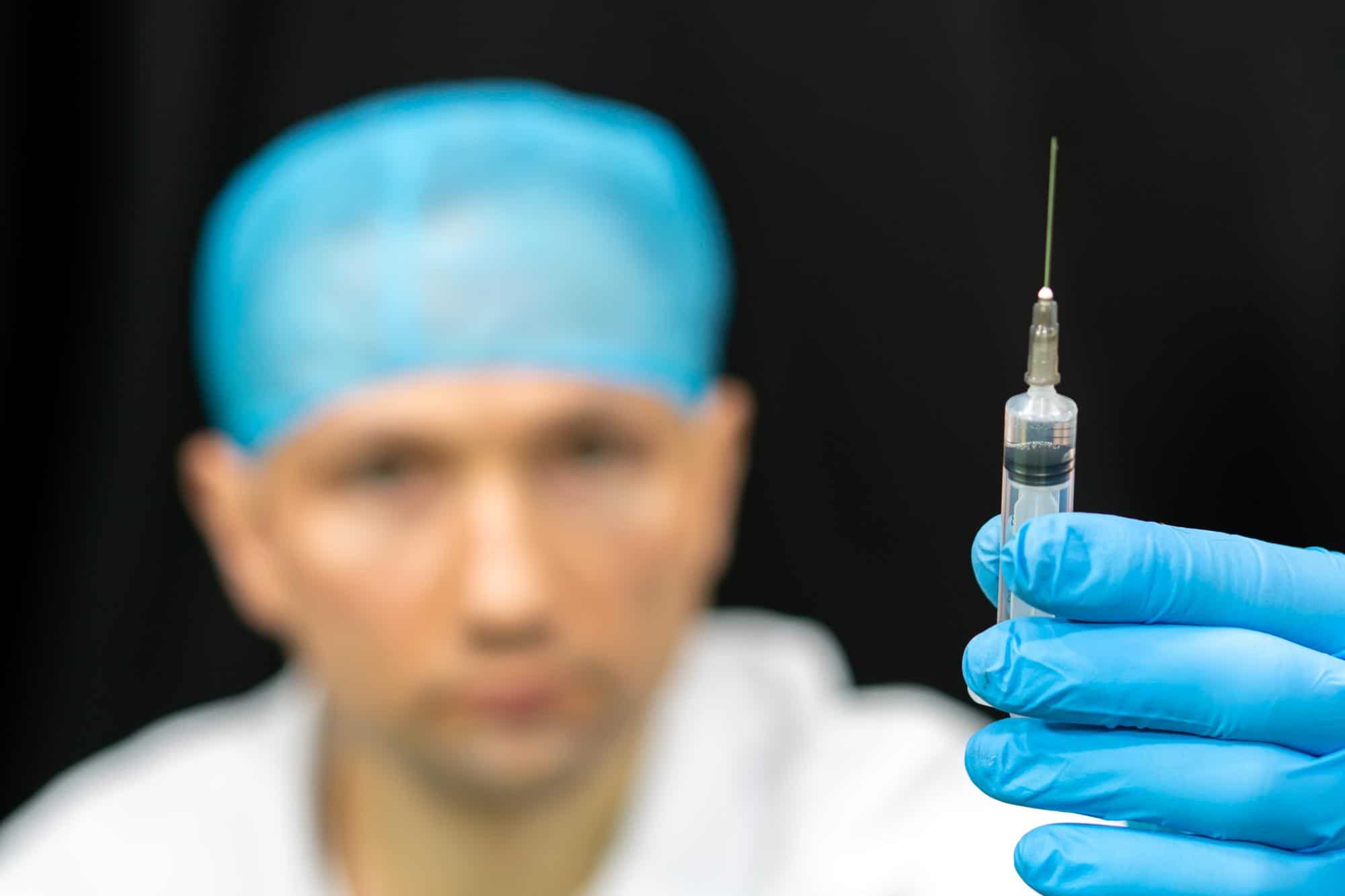 A doctor holds up a syringe and checks the dosage before proceeding with the treatment.