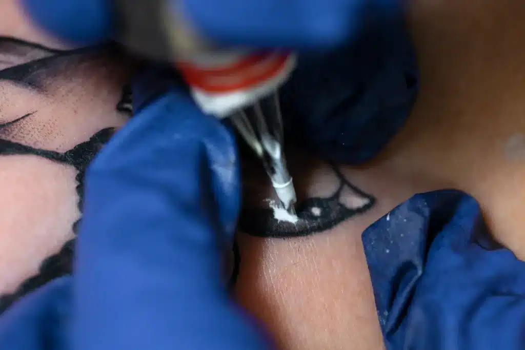 tattoo artist carefully draws the design on her skin