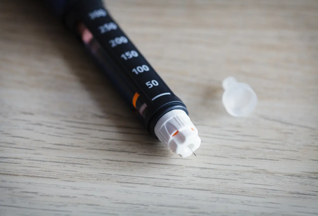 A pen, looks like Cimzia or other injectable treatments, is on the table.