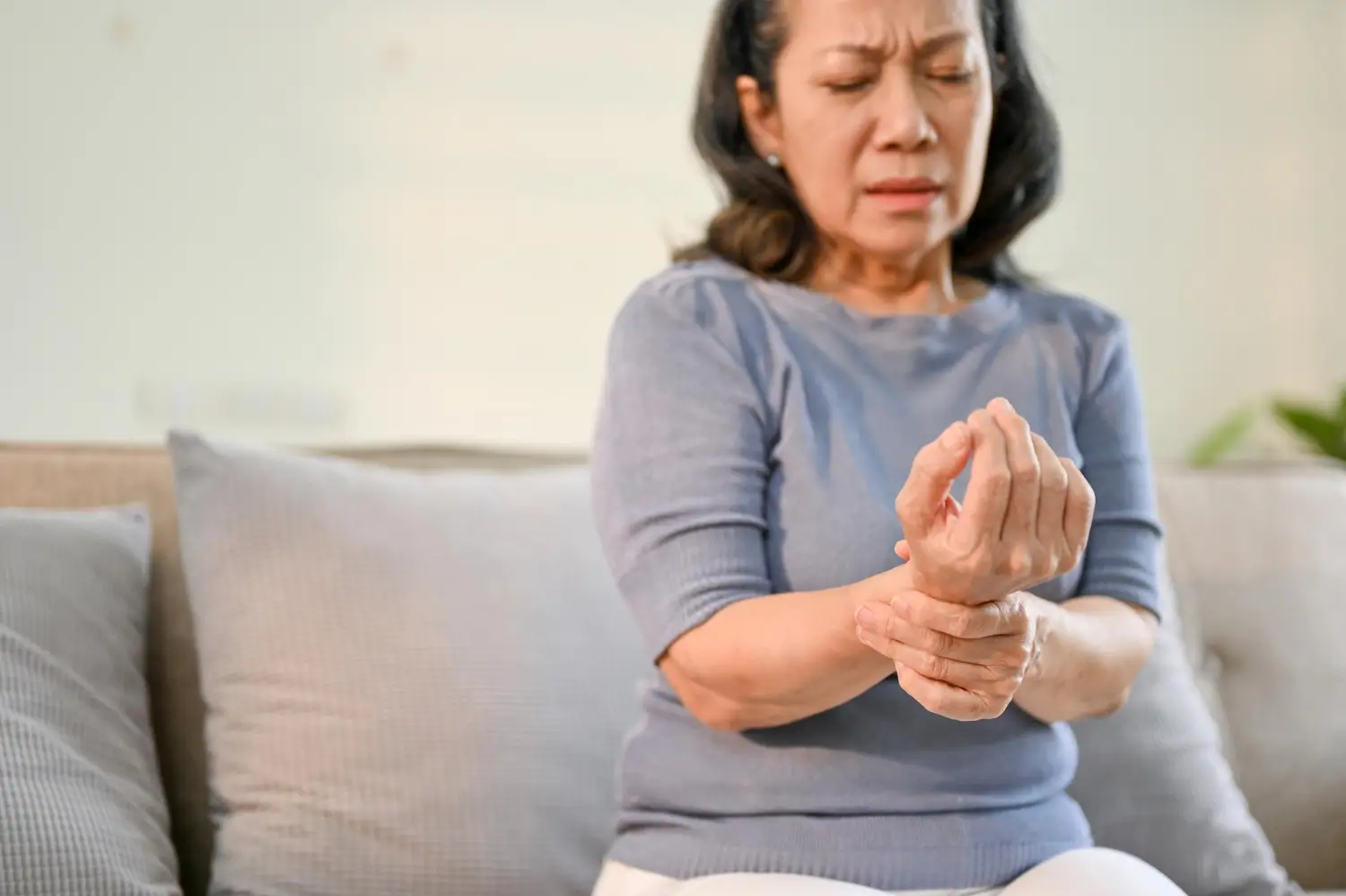 Mid-aged woman holds onto her wrist to manage pain.