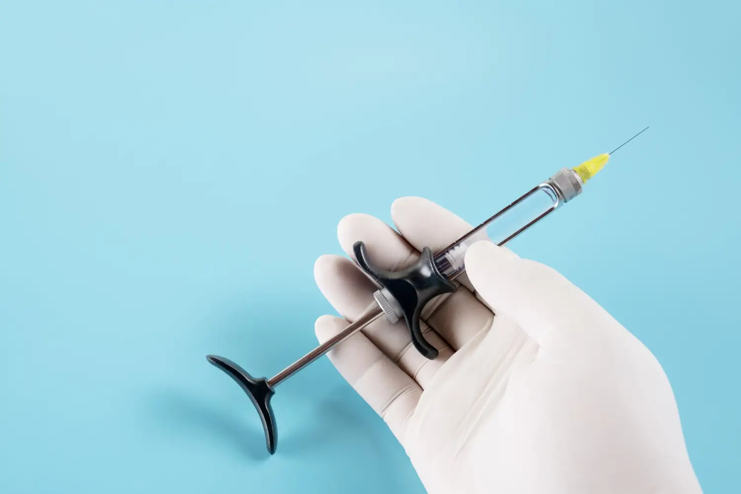 A gloved hand holds an empty syringe, maybe for injecting a treatment such as Cimzia.