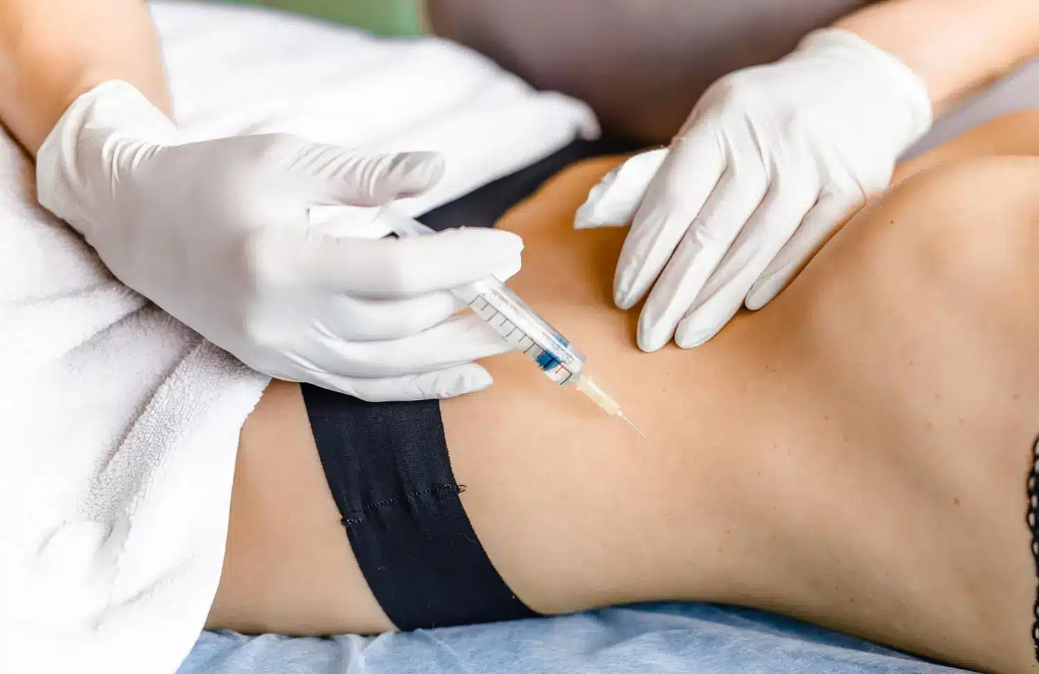 A professional in sterile gloves performs an injection into a patient's abdomen, potentially an autoimmune treatment or vitamin shot.