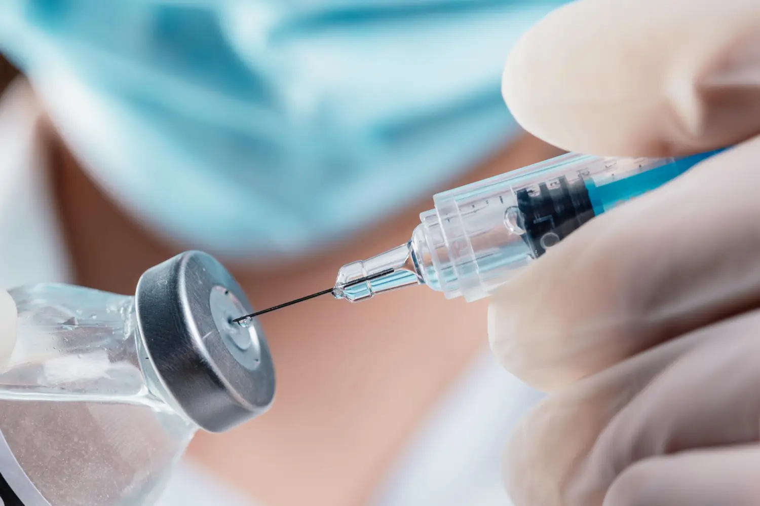 A healthcare professional fills a syringe from a vial of treatment, could be Cimzia or other inejctables.