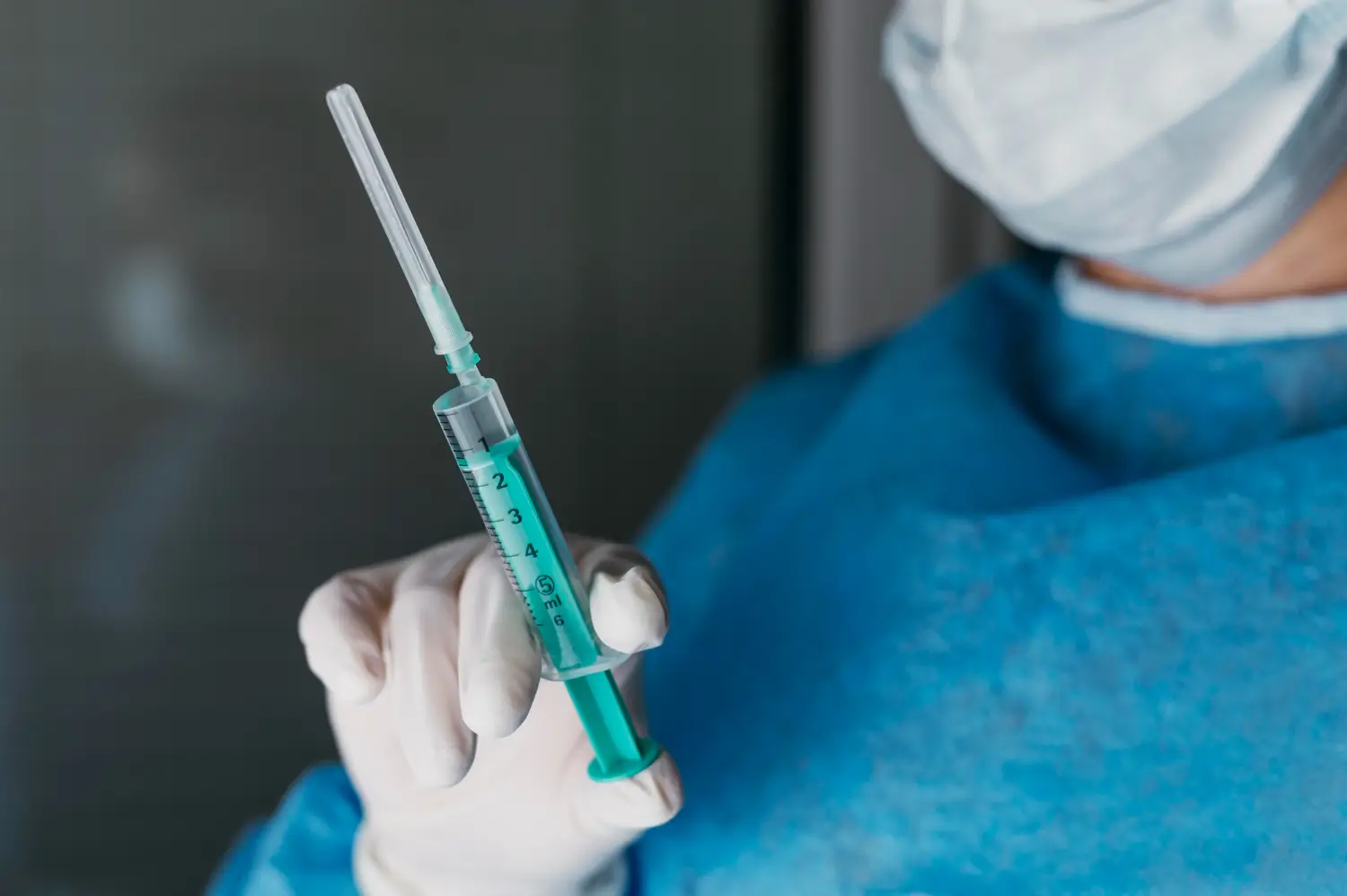 medical professional holding a syringe filled with the treatment.