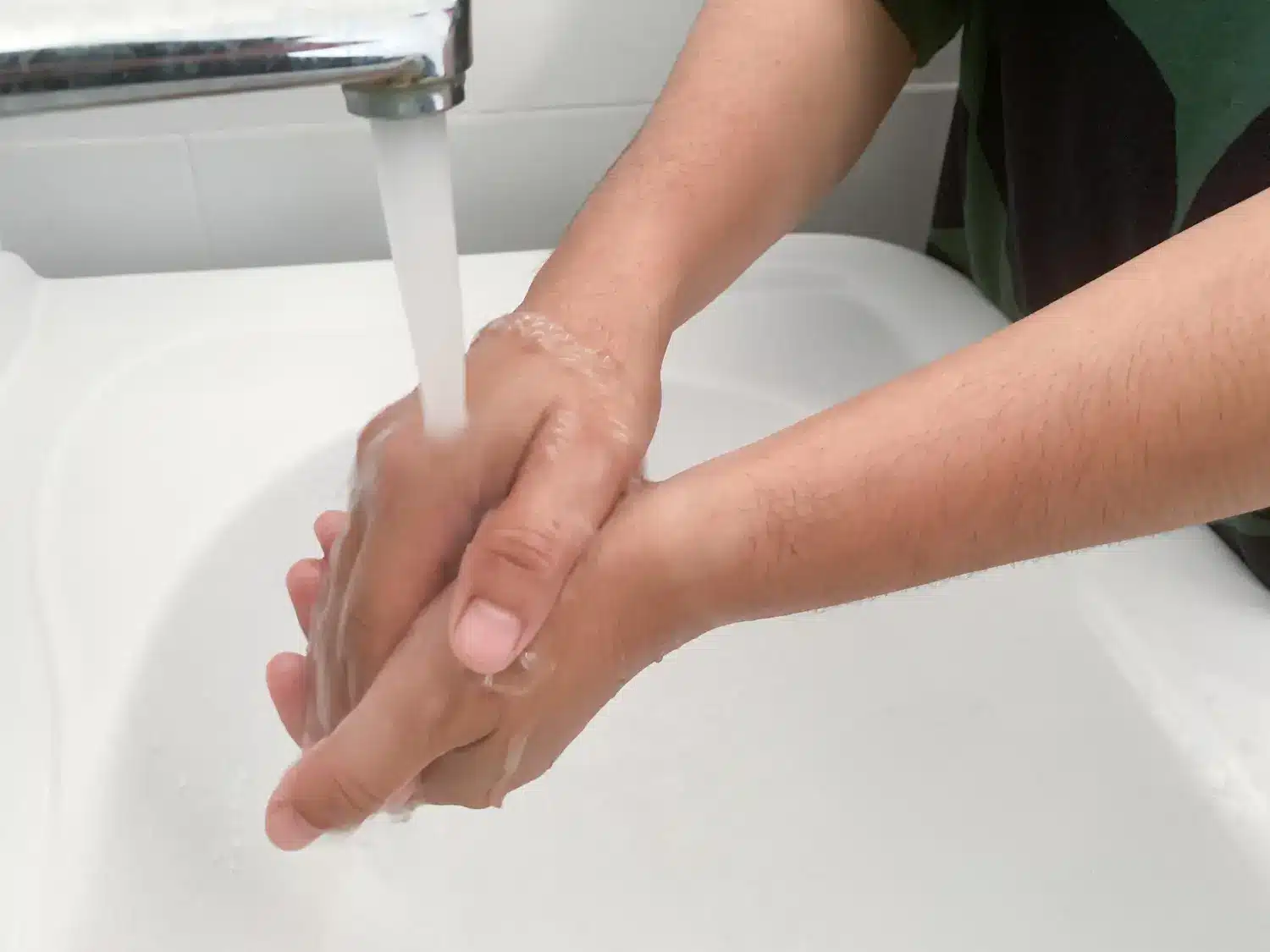An individual washing hands with soap and water to ensure proper hygiene. 