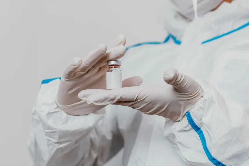 Doctor wearing gloves holds a vial of cosmetic injectable, probably a botulinum toxin like Dysport.