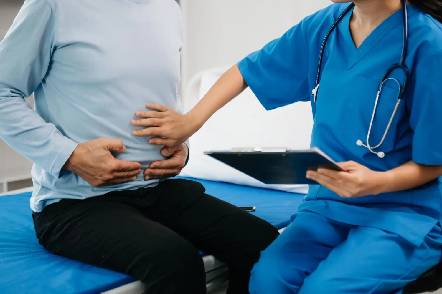The doctor is checking on the patient's stomach for follow-up checkup.