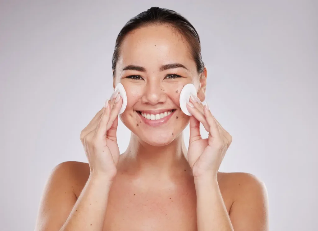 A happy woman cleansing her skin for proper care.