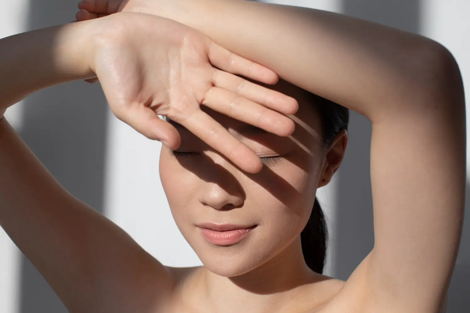 Woman shields her face from the sun, highlighting the need for UV protection and daily SPF skincare.