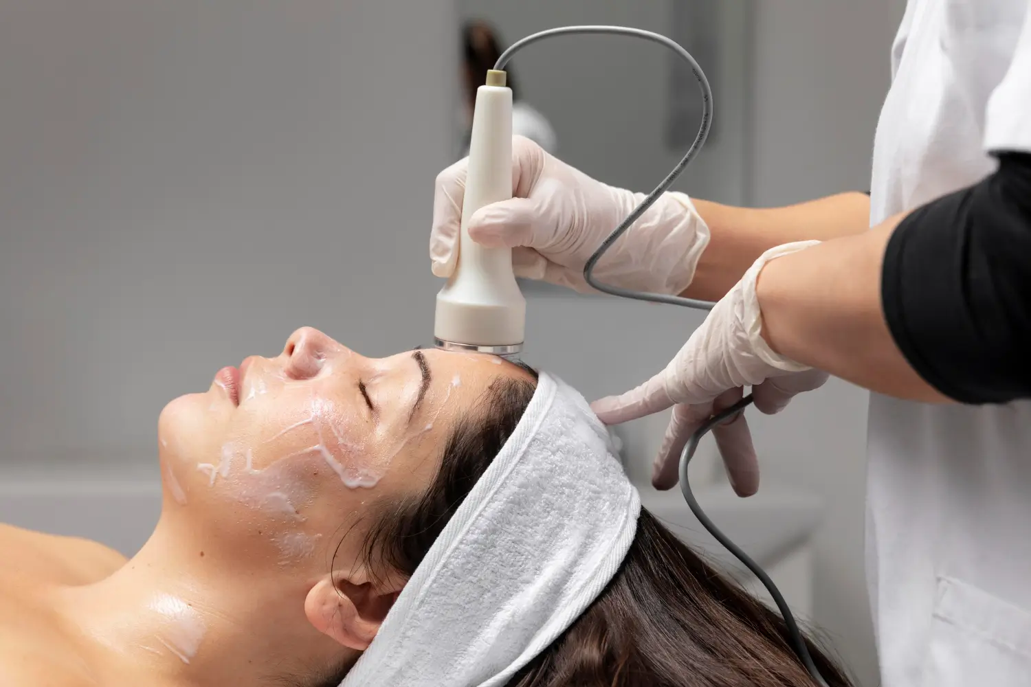 Woman lies down as she gets a facial treatment for tighter skin.