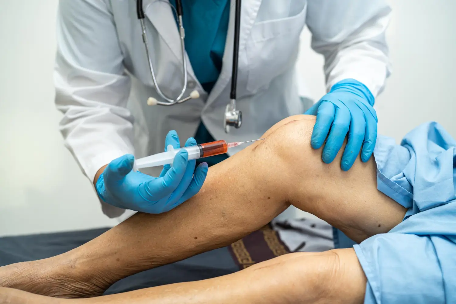 Doctor injects a knee treatment, probably Orthovisc or other injectable treatments, to the patient's joint.