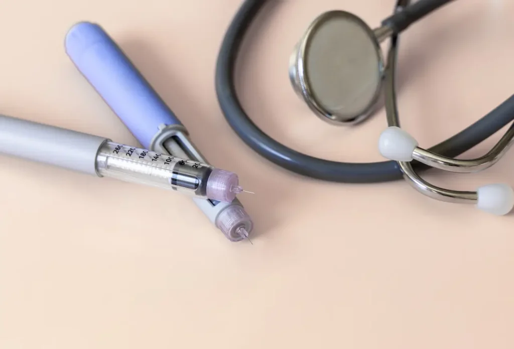 A stethoscope and insulin pens that symbolize diabetes management and comprehensive medical care.
