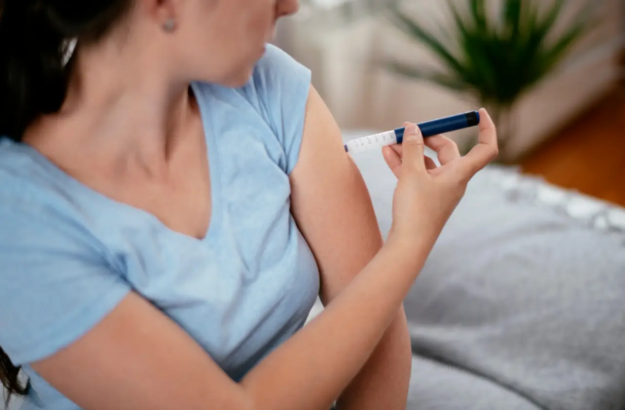 Woman administering a self-injection with a medication pen, a common method for diabetes treatment such as Mounjaro or Wegovy.