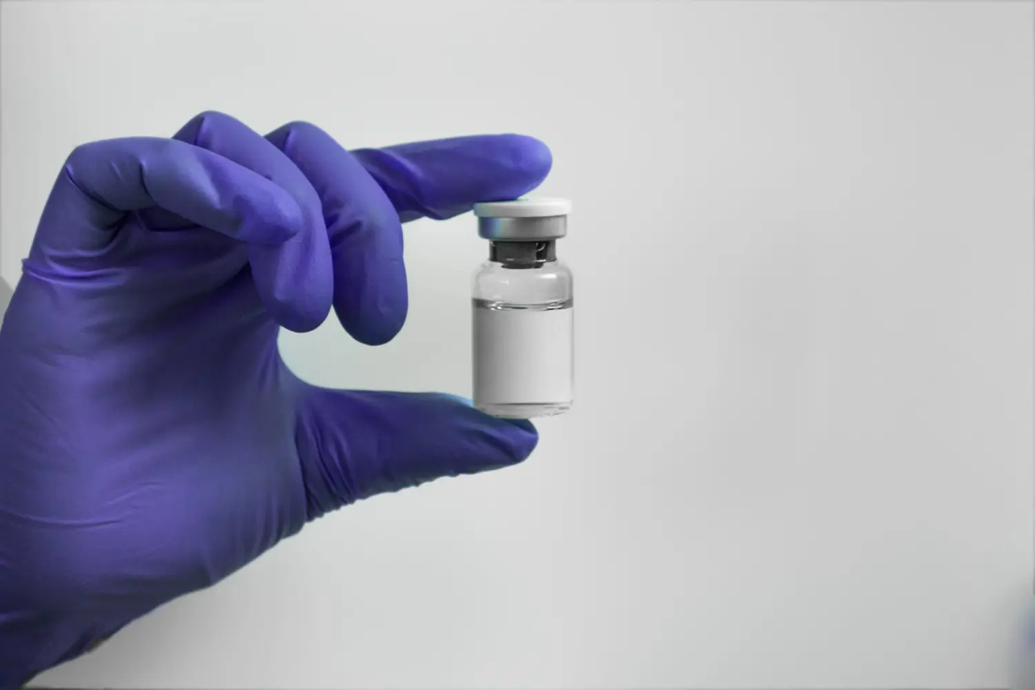 Doctor with gloved hands hold the vial of injectable treatment.