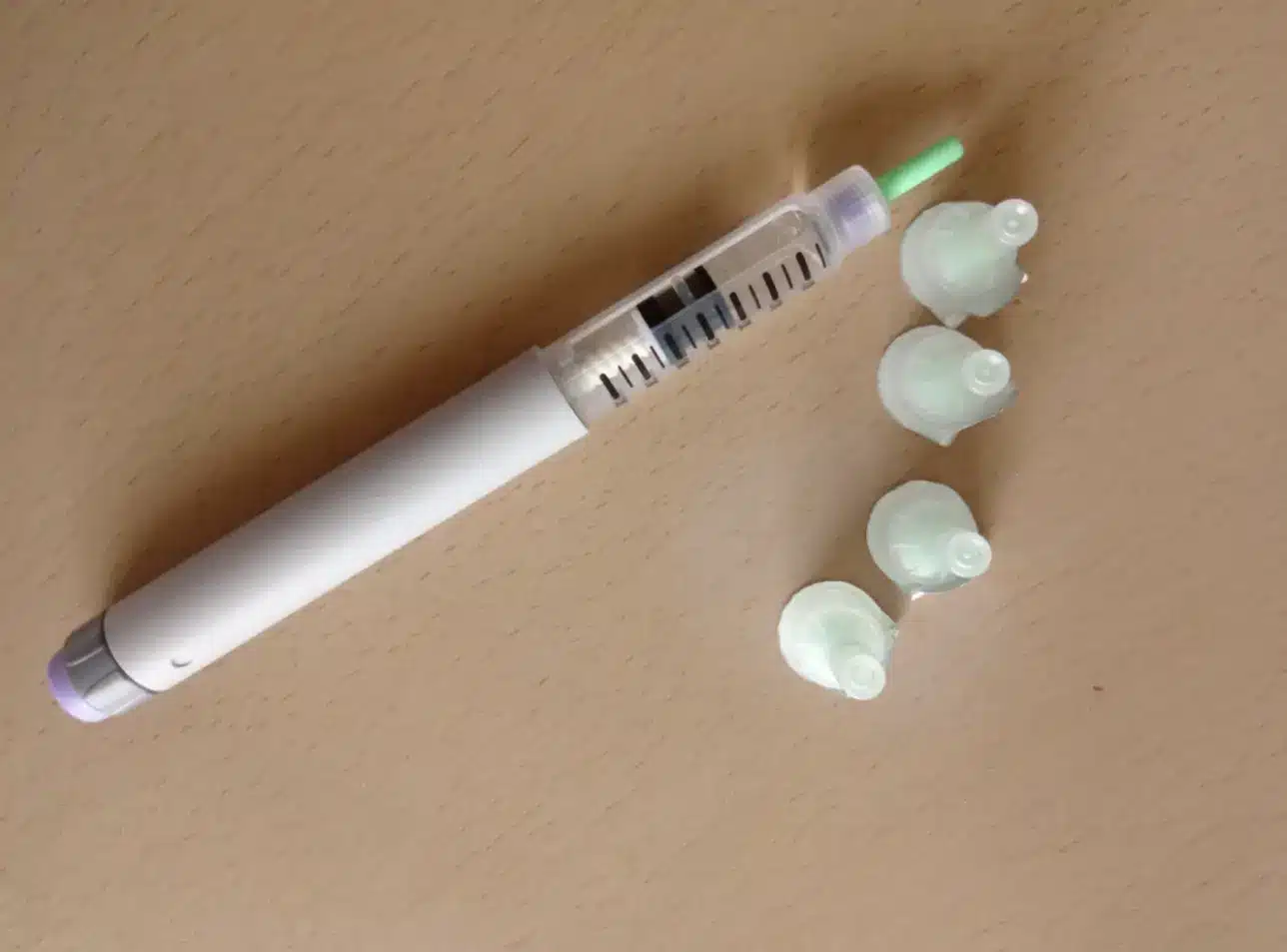 Insulin pen for blood sugar control with many lids on the table.
