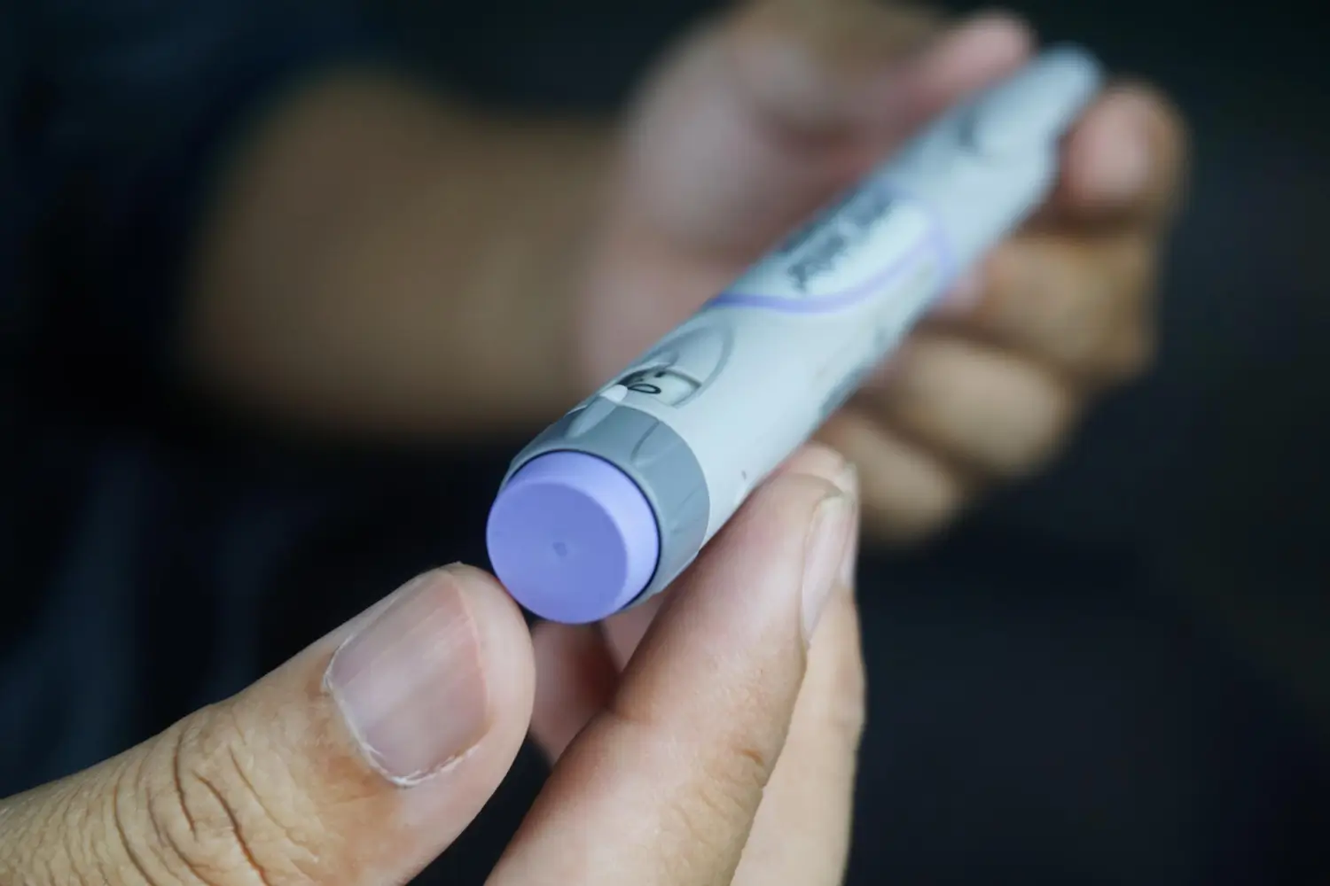 Person holding an insulin pen, probably for diabetes control with Mounjaro or other treatments.