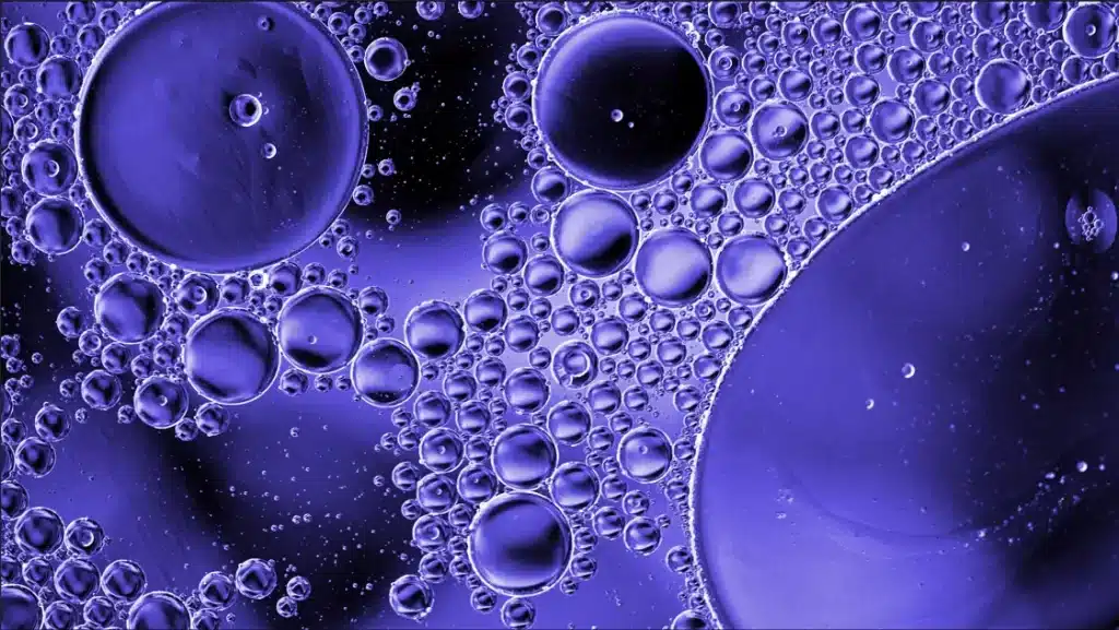 Close-up image of various-sized oil bubbles clustered together on a surface.